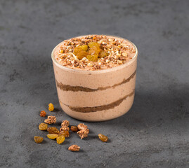 Tiramisu, mascarpone cheese biscuit chocolate nut dried fruit in a glass jar on a dark gray background