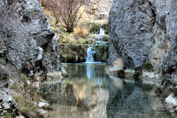 Fototapeta na wymiar Stream of crystal clear water, between rocks reflected in the water between Frías de Albarracín and Calomarde