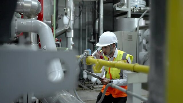 Chief Industrial Engineer in Hard Hats used Laptop Computer check and control machine while Sitting in the Heavy Industry Manufacturing Factory.man at work and maintenance engineer concept.