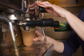 Fototapeta na wymiar Barista makes coffee in a craft glass in a coffee machine. Small business mini coffee shop drink takeaway