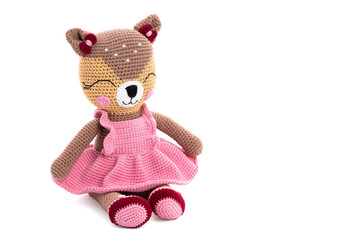 Knitted cat toy in a pink dress and shoes sitting over white background with soft shadow