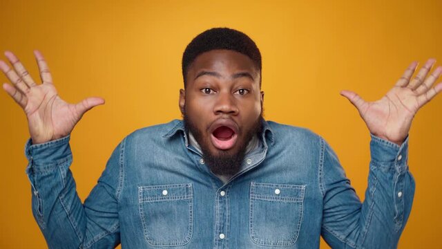 African american young man showing his mind is blown against yellow background