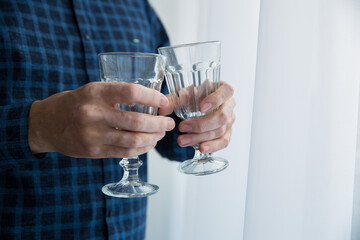 a man in a blue shirt holds empty glasses of vitiligo photo front photo close up