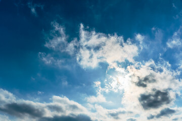 Naklejka na ściany i meble The rays of the sun break through the clouds.Blue sky with white feather clouds. Panoramic view of the blue sky with clouds in motion.Nice weather with clear skies. Panorama of the sky in motion