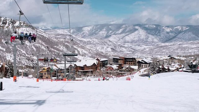 USA. Aspen. March 2021.Panoramic view on town in Colorado during winter season. People on skis and snowboards on the slopes of the ski resort. Ski elevator on snow mountain. 