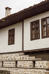 Old typical traditional Bulgarian house with white walls, wooden windows, architecture from Bulgarian National Revival period.
