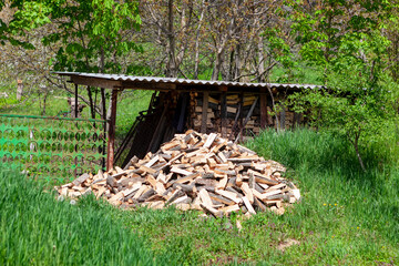 Pile of chopped firewood on the green grass . Rustic yard with firewood 