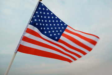 Miniature flag of American is isolated on a blue sky. Politics, learning a foreign language. 4 July. Memorial Day.