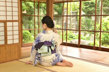 古民家の和室で正座する浴衣を着た若い女性の後ろ姿	