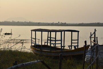 a boat captured closely during sunset , parked near a lake.
