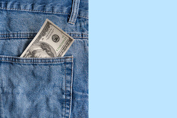 Money in pocket. Dollar bill in jeans pocket on a blue background. Copy space. Concept of making...
