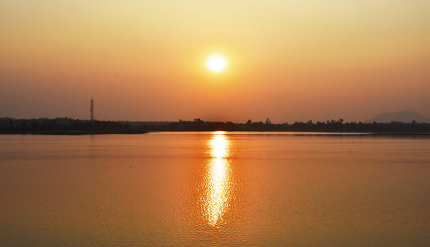Sunset captured near a lake with yellowish reflection in water.