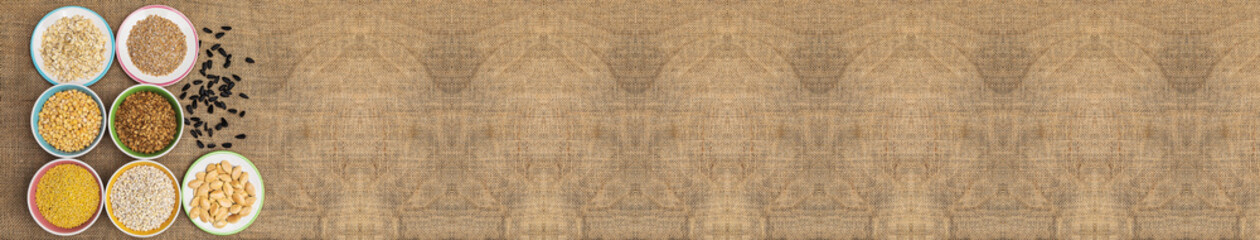 Portions of various cereals of wheat, peas, buckwheat, millet, oatmeal, barley in a multi-colored dish against a background of burlap and scattered seeds and flakes, banner, copispase, flat lay