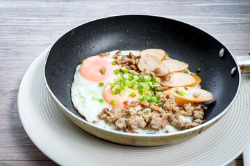 Pan-fried egg with toppings, hot breakfast in cooking served on table in morning.