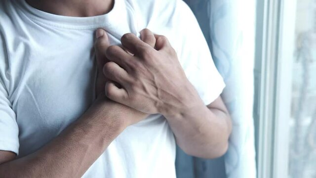 young man suffering pain in heart and holding chest with hand 