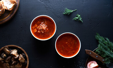 Obraz na płótnie Canvas two dishes of borscht stand on a black table