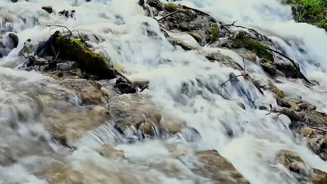 Close-up of flowing water of a mountain stream. Small river waterfall. Clear mountain water in summer or spring time. 