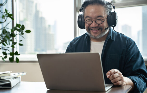 Asian middle aged man sitting at home working on video call. Work from home concept