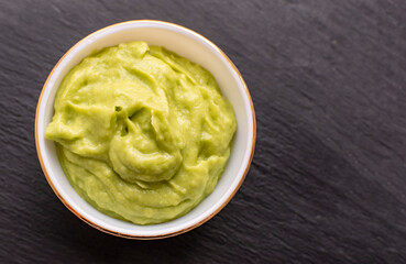Gluacomole with chips on a black stone background. Gastronomic concept.