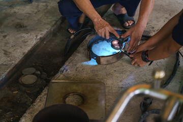 Asian worker using plasma cutter for cutting modified bottomless portafilter
