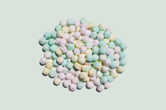 after dinner mints in pink yellow and green colors in a heap pile on a light off white studio space as food scene