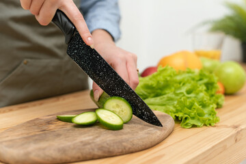 Beautiful young woman is preparing vegetable salad in the kitchen. Dieting Concept. Healthy Lifestyle. Cutting ingredients on table. Healthy Food. Nutrition Tips. Close up