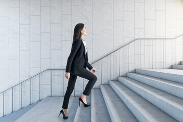 Road to success concept with businesswoman climbing the stairs in modern loft style hall.