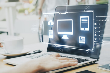 Hologram desktop with different icons in it and hands on the laptop in the background. Big data and technology concept