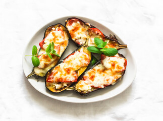 Mediterranean style baked eggplant with mozzarella and tomatoes on a light background, top view