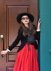 Fashion portrait stylish pretty woman outdoor. Street fashion. Red lipstick. Black hat Red skirt.