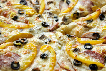 Pizza with chesse, ham, yellow bell pepper, olives and mushrooms closeup