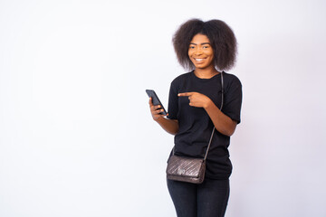 happy attractive young black woman with a smile on her face gestures to her phone