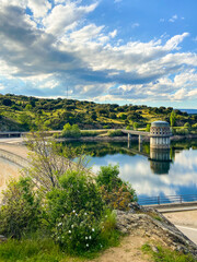 Fototapeta premium Constructed dam containing water that reflects the sky with a green environment in Madrid, Spain.