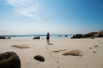 young woman walking alone on the beach of the beautiful deserted island of Areoso, in the Rías Baixas.