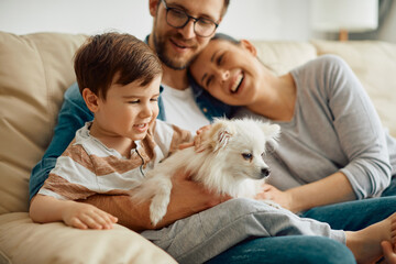 Happy family enjoying with their dog while relaxing at home.
