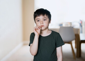 Young boy with dirty face of chocolate putting thump in his mouth,High key portrait Kid enjoy...