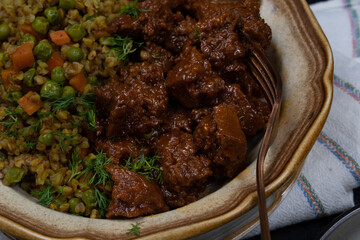 Vegan buckwheat and vegetables with seitan on plate, dark table, copy space