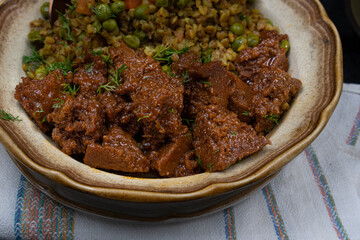 Vegan buckwheat and vegetables with seitan on plate, dark table, copy space