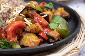 Vegan buckwheat and seitan with roasted vegetables on cast iron dish