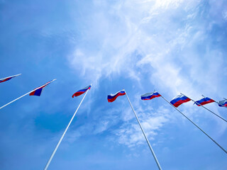 Russian flags are on the blue sky, background. High flagpoles are pointing up. Beautiful wallpaper...
