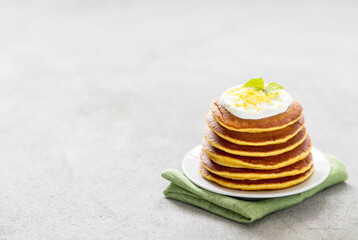 Vegan breakfast lemon pancakes with zest on a plate on a light gray background copy space