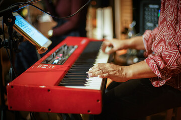 A close-up picture of a musician playing a red keyboard