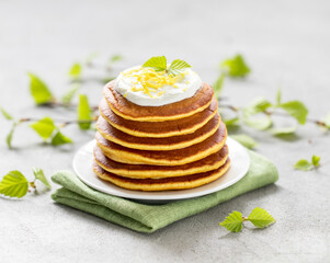 Obraz na płótnie Canvas Vegan breakfast lemon pancakes with zest on a plate on a light gray background