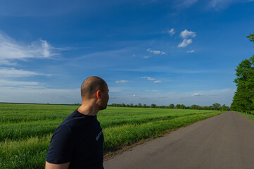 silhouette of a farmer from the back looking into the distance at the fields. May. Forty years old.