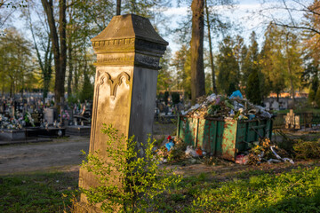 Fototapeta na wymiar old grave in the cemetery, an overcrowded garbage can in the distance
