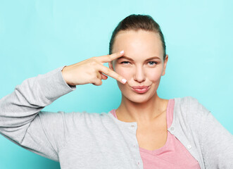 Portrait of a pretty young woman showing the peace sign on blue background.