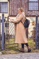 portrait of a beautiful Caucasian woman in the park, beige cashmere coat, black leather backpack, casual street style outfit, daily fashion