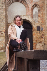 Woman sitting on a wooden fence, old castle background
