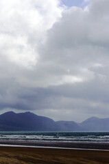 Dinas Dinlle beach north Wales. Dramatic cloudy winter landscape with view over the Llyn peninsula  mountains. Sky and sea on a stormy winters day. Grey cloudy skies provide copy space.