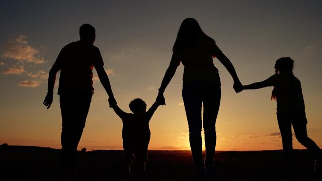 Silhouette of happy family. Silhouette of group of people in park hiking. Happy family concept. Parents and children in park at sunset. Happy family hiking. Silhouette of people at sunset.